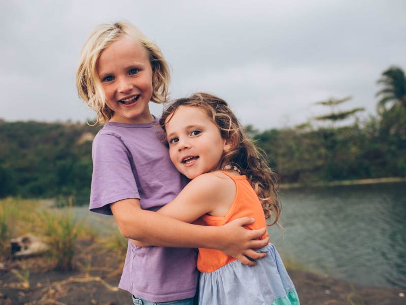 Großer Bruder umarmt seine kleine Schwester.