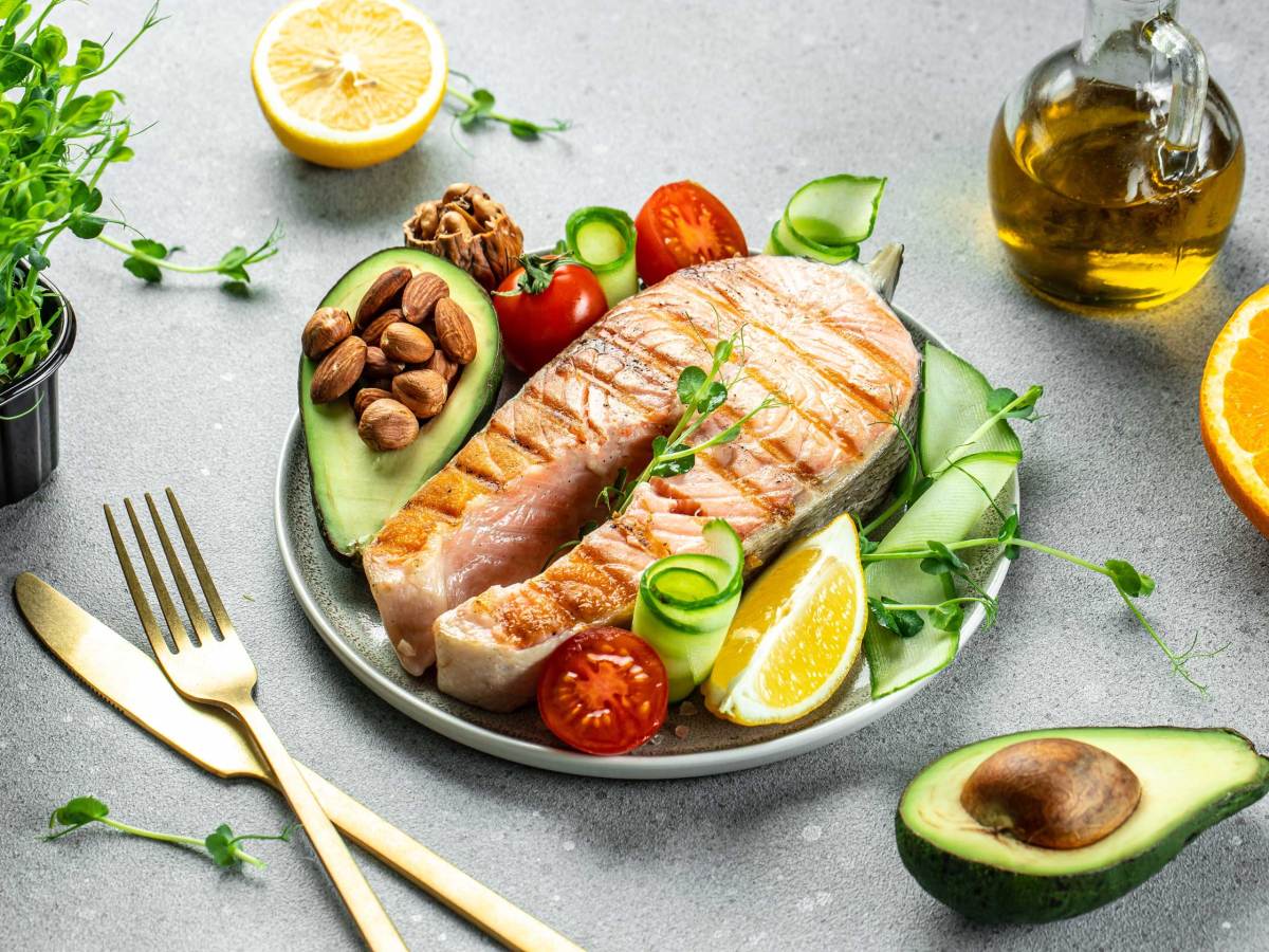 Gegrilltes Lachs-Fischsteak, Avocado, Mandeln, &Ouml;l und frischer Gem&uuml;sesalat. Ketogene Di&auml;t. Kohlenhydratarmes und fettreiches Gericht. Gesunde Ern&auml;hrung Konzept.
