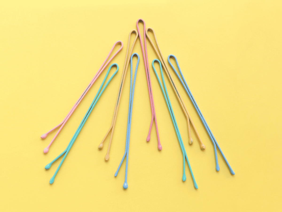 Draufsicht auf bunte pastellfarbene Haarspangen auf gelbem Hintergrund.