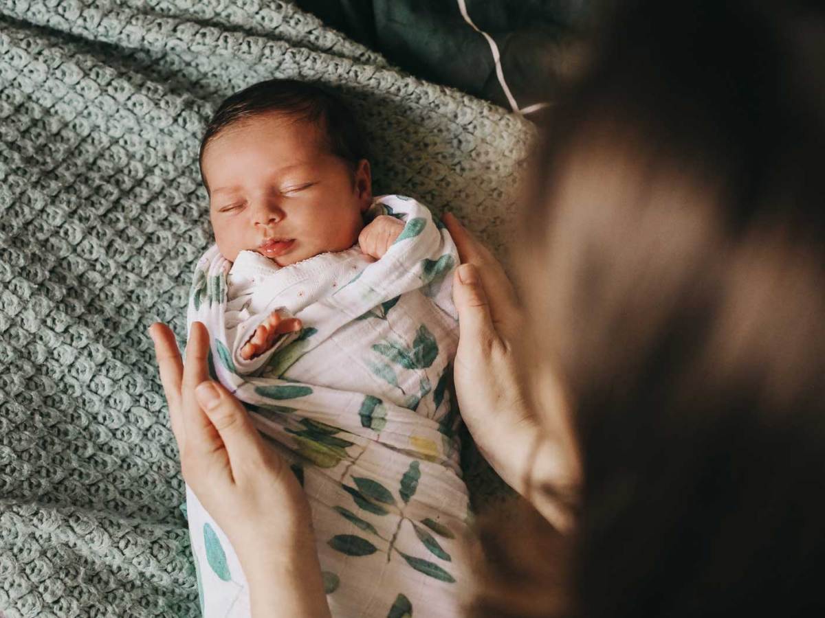 Mutter hat ihr neugeborenes Baby in ein Tuch gewickelt.