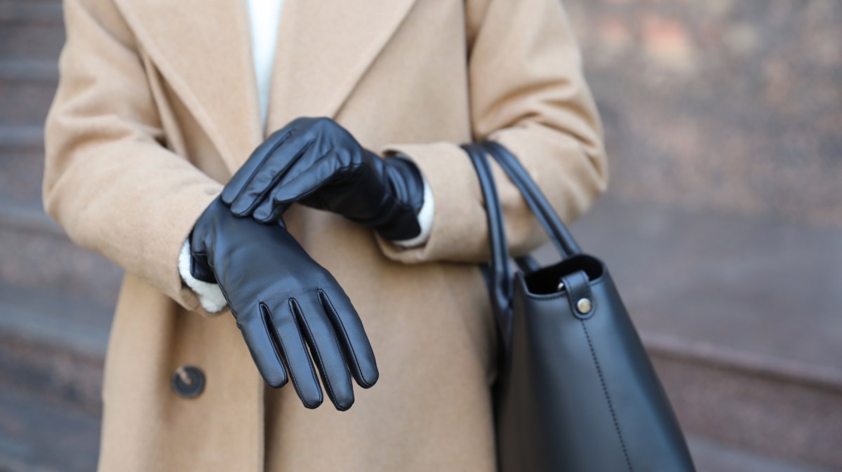 Frau zieht schwarze Lederhandschuhe an.