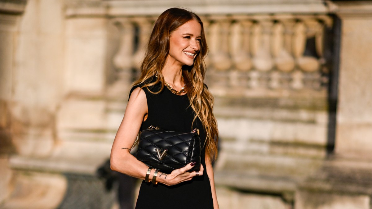 Frau, die ein elegantes schwarzes Etuikleid mit goldenem Schmuck trägt