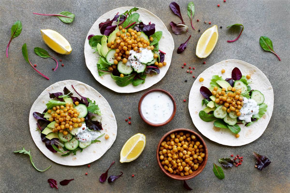 Veganer Tortilla-Kichererbsen-Avocado-Salat mit Gurke und Joghurtsoße. Gesundes Clean Eating Food Konzept. Flachgelegte Zutat.