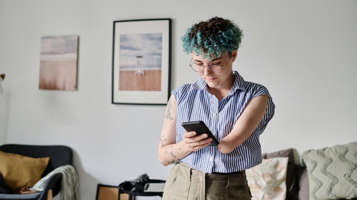 Frau mit Handy in der Hand, die auf den Bildschirm schaut