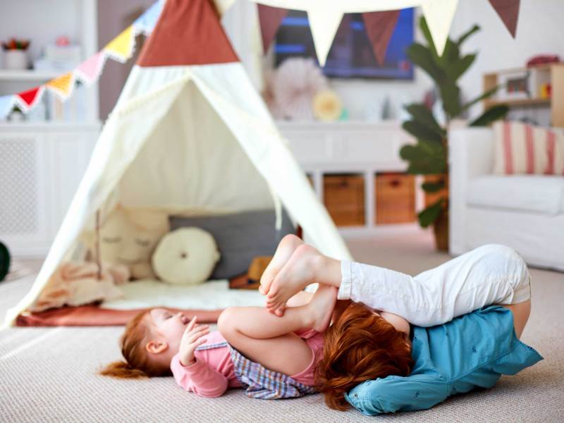 Zwei Kinder toben und spielen in einem Zimmer.