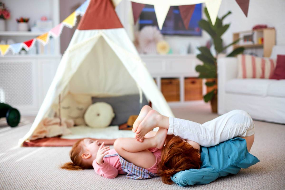 Zwei Kinder toben und spielen in einem Zimmer.