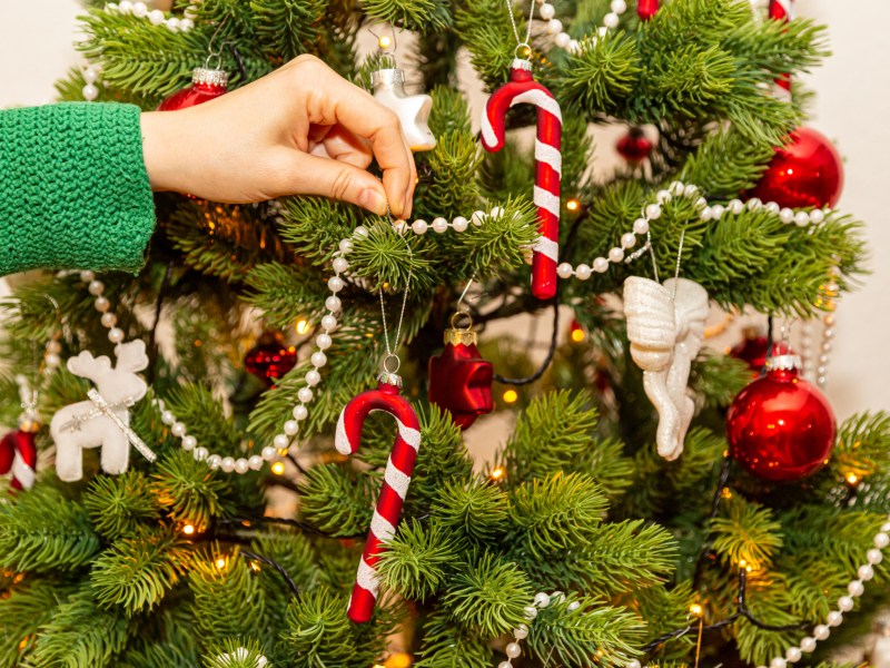 Eine Frau schmückt einen Tannenbaum.