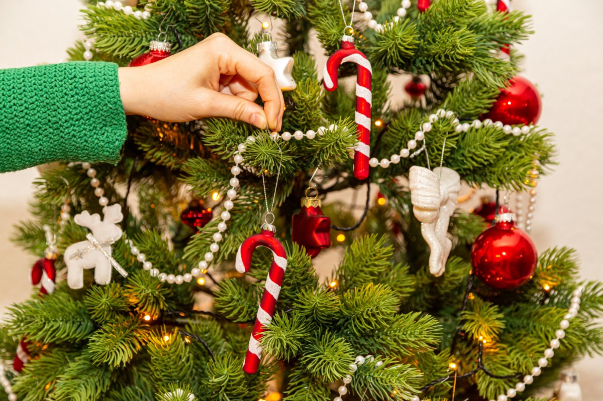 Eine Frau schmückt einen Tannenbaum.