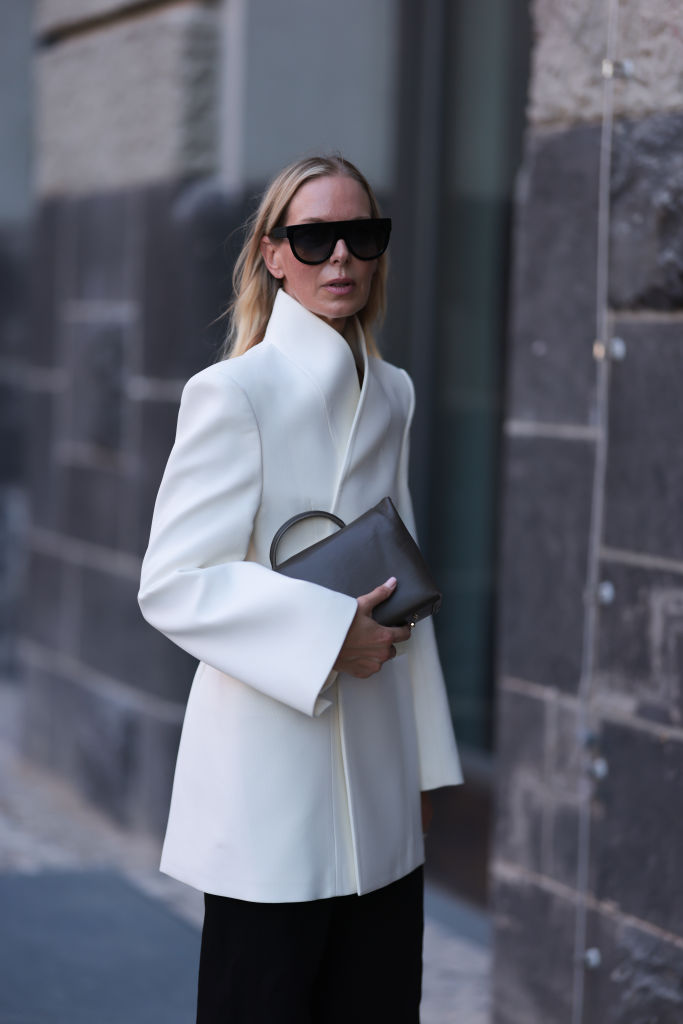 Blonde Bloggerin in einem weißen Wintermantel.