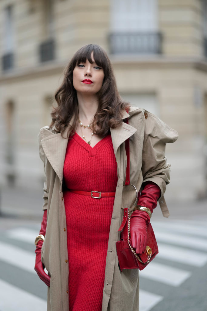 Brünette Frau mit rotem Strickkleid und Trenchcoat.