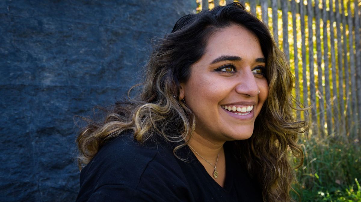 Lächelnde Frau mit dunklen Haaren und Locken.