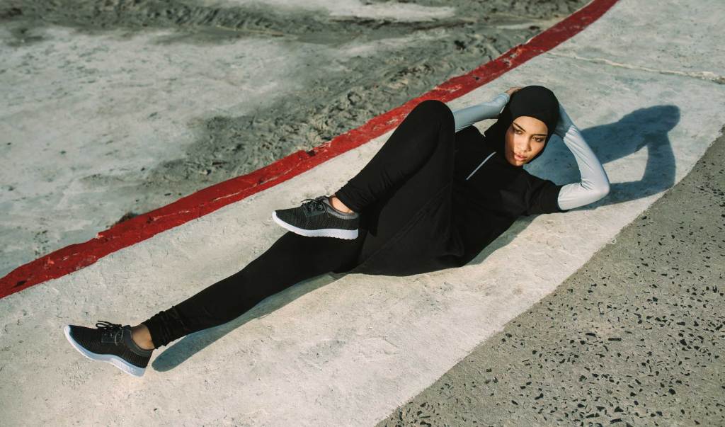 Bikini-Body-Challenge: Bicycle Crunches für den Bauch Sportlerin mit Hidschab beim Bicycle Crunche-Training