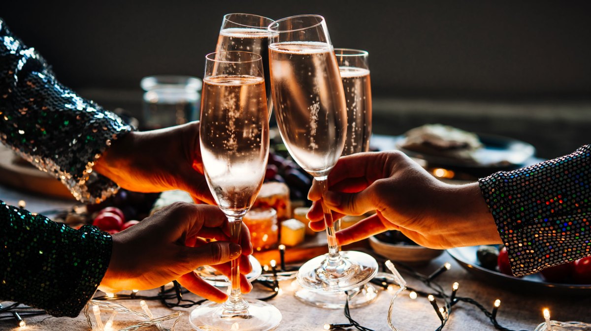 Nahaufnahme von Händen mit je einem Sektglas, die anstoßen.