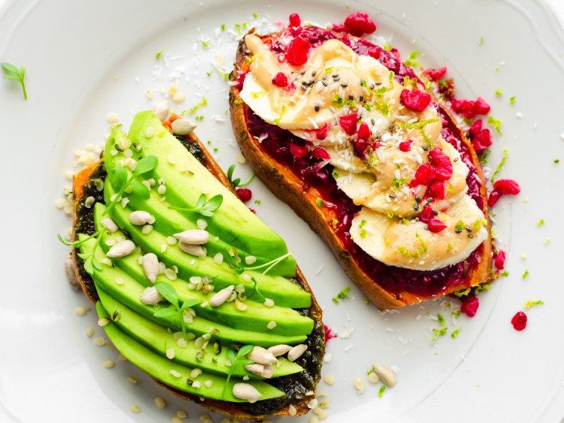 Zwei Scheiben Süßkartoffel-Toast, links mit Avocadoscheiben, rechts mit Banane und Marmelade