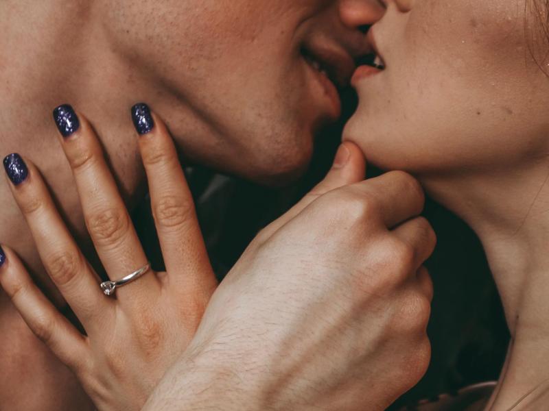 Nahaufnahme: Mann küsst Frau leidenschaftlich. Sie streicht mit ihrer Hand über seinen Hals.