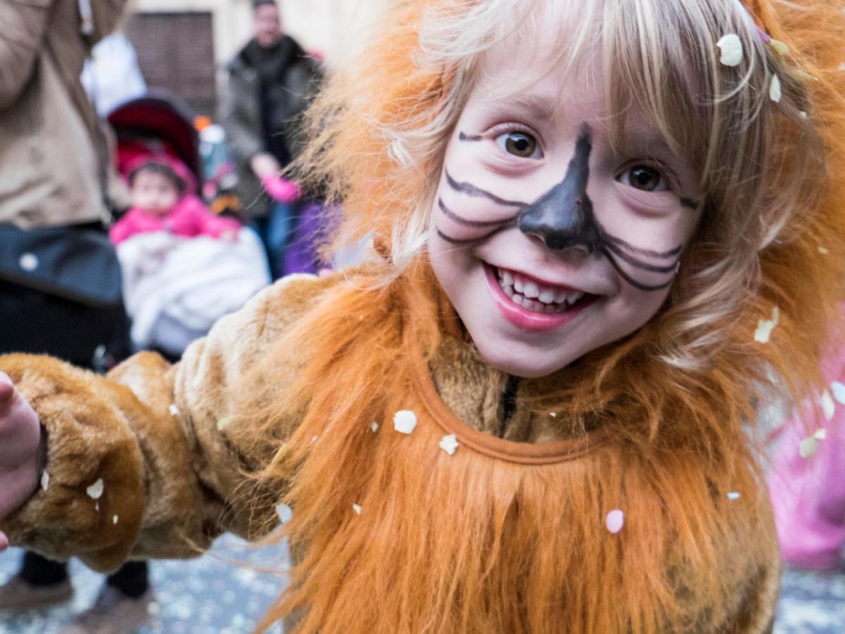 Kleines Kind mit Löwenkostüm steht auf der Straße.
