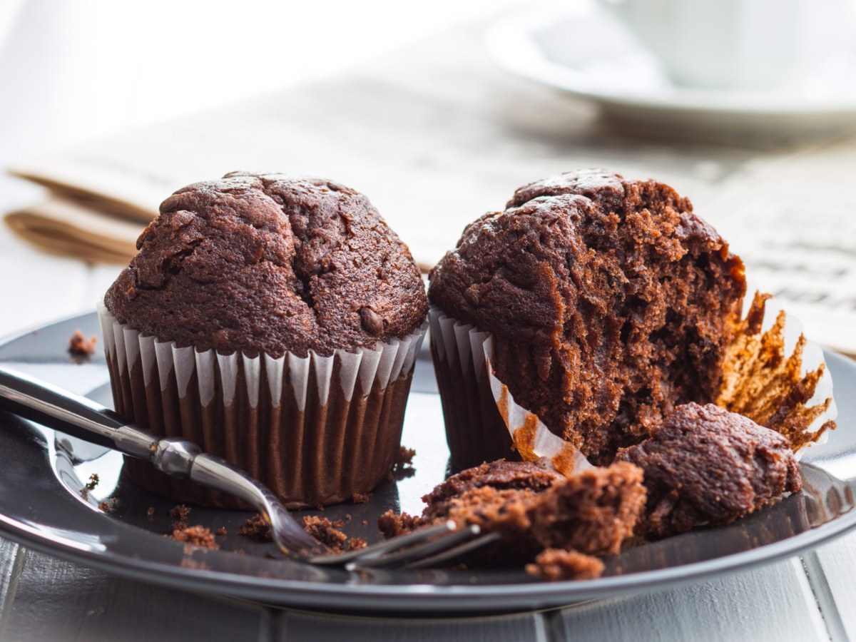 Zwei Schokomuffins auf einem grauen Teller, einer wurde angebissen.