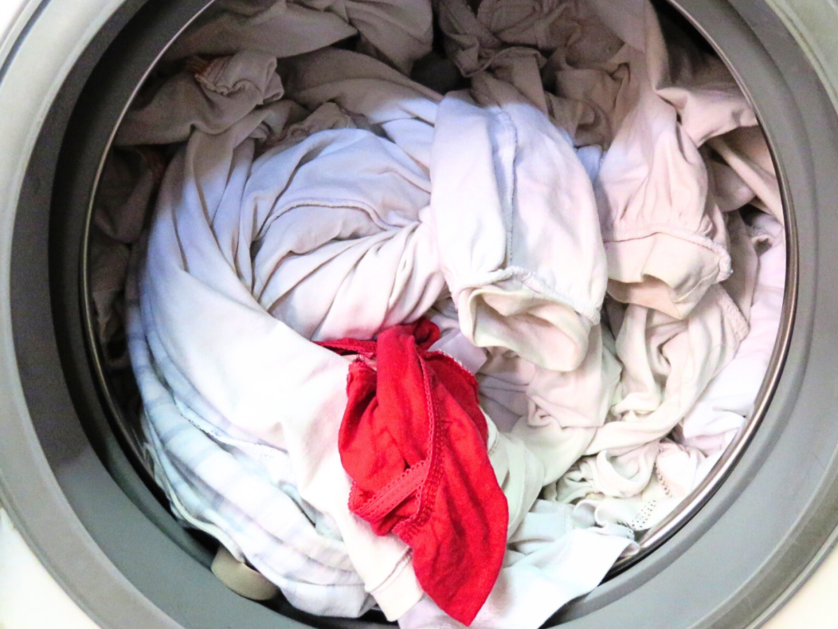Rotes Textilstück in einer Trommel mit weißer Wäsche.