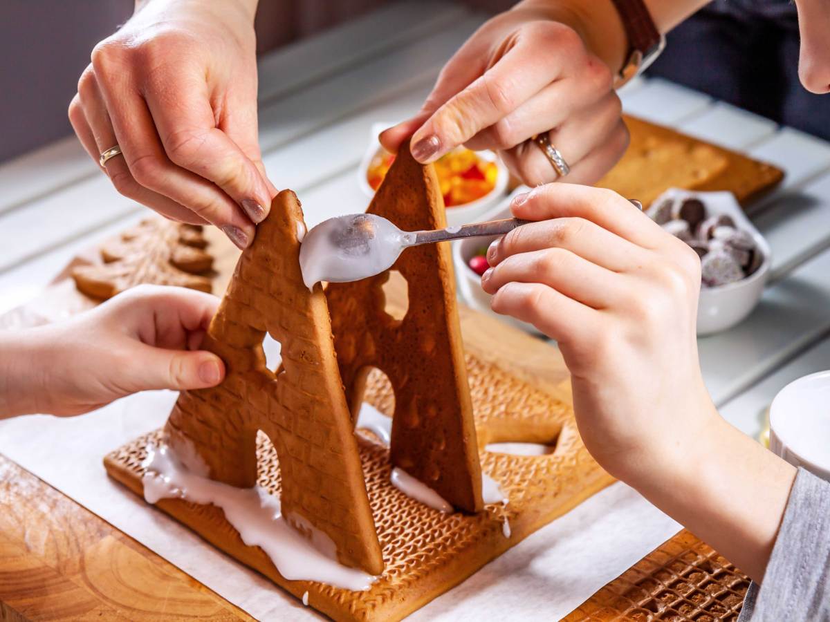 Familie baut gemeinsam ein Lebkuchenhaus.