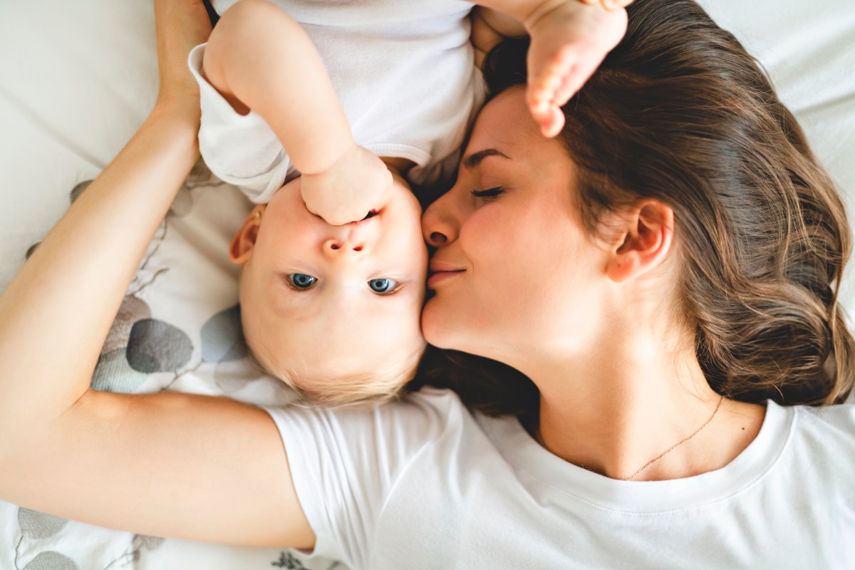 Mutter mit ihrem Baby auf dem Bett liegend.