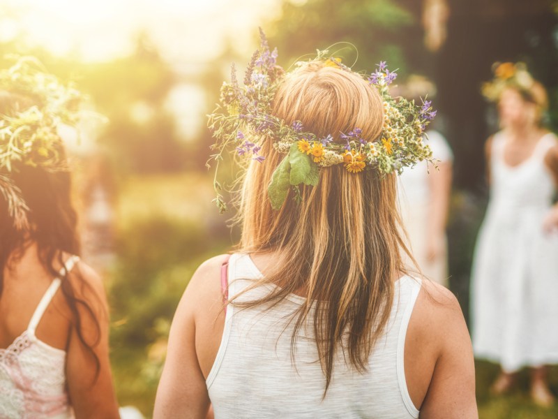 Mädchen feiern Mittsommer und tragen Blumenkränze.