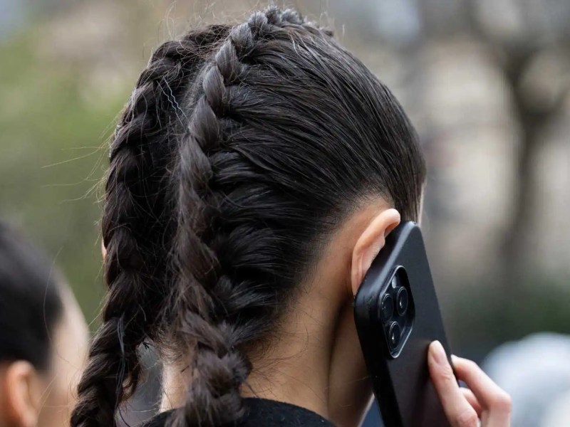 Frau mit schwarzen Haaren hat zwei geflochtene Dutch Braids