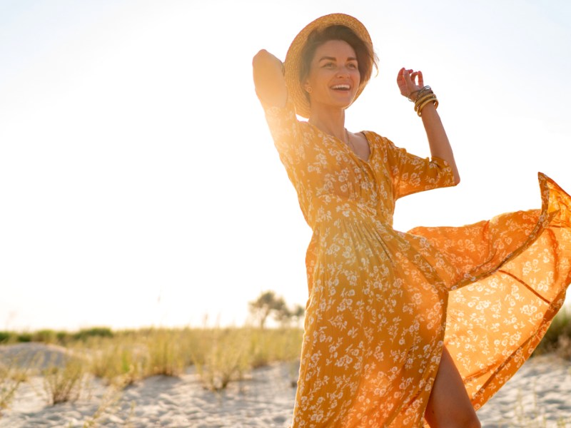 Frau in Kleid am Strand; eines der Sternzeichen, die den Sommer lieben