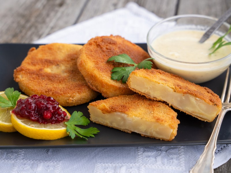 Vegetarische Sellerie-Schnitzel auf schwarzem Teller.