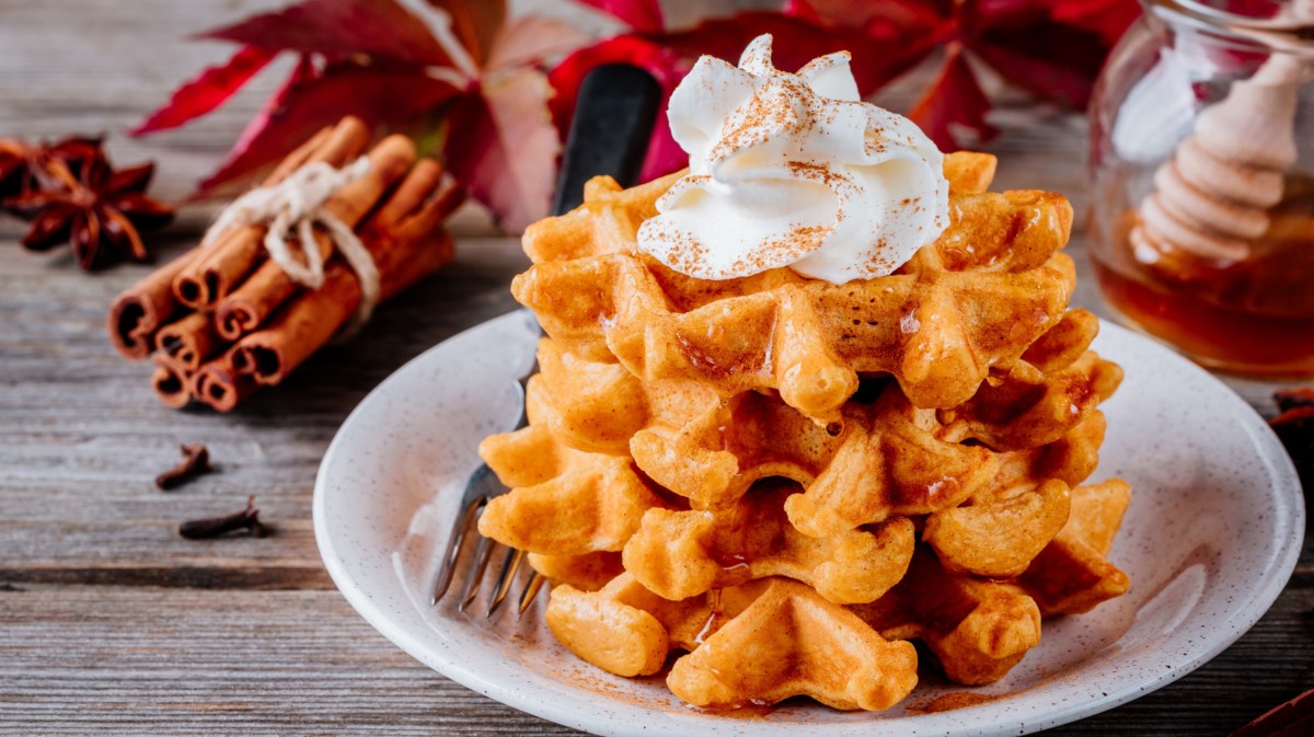 Kürbis-Waffeln mit Sahne auf weißem Teller.