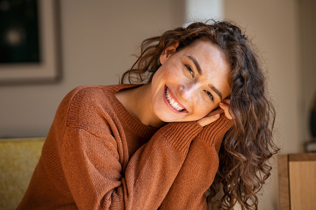 Junge Frau mit Locken lächelt in die Kamera.