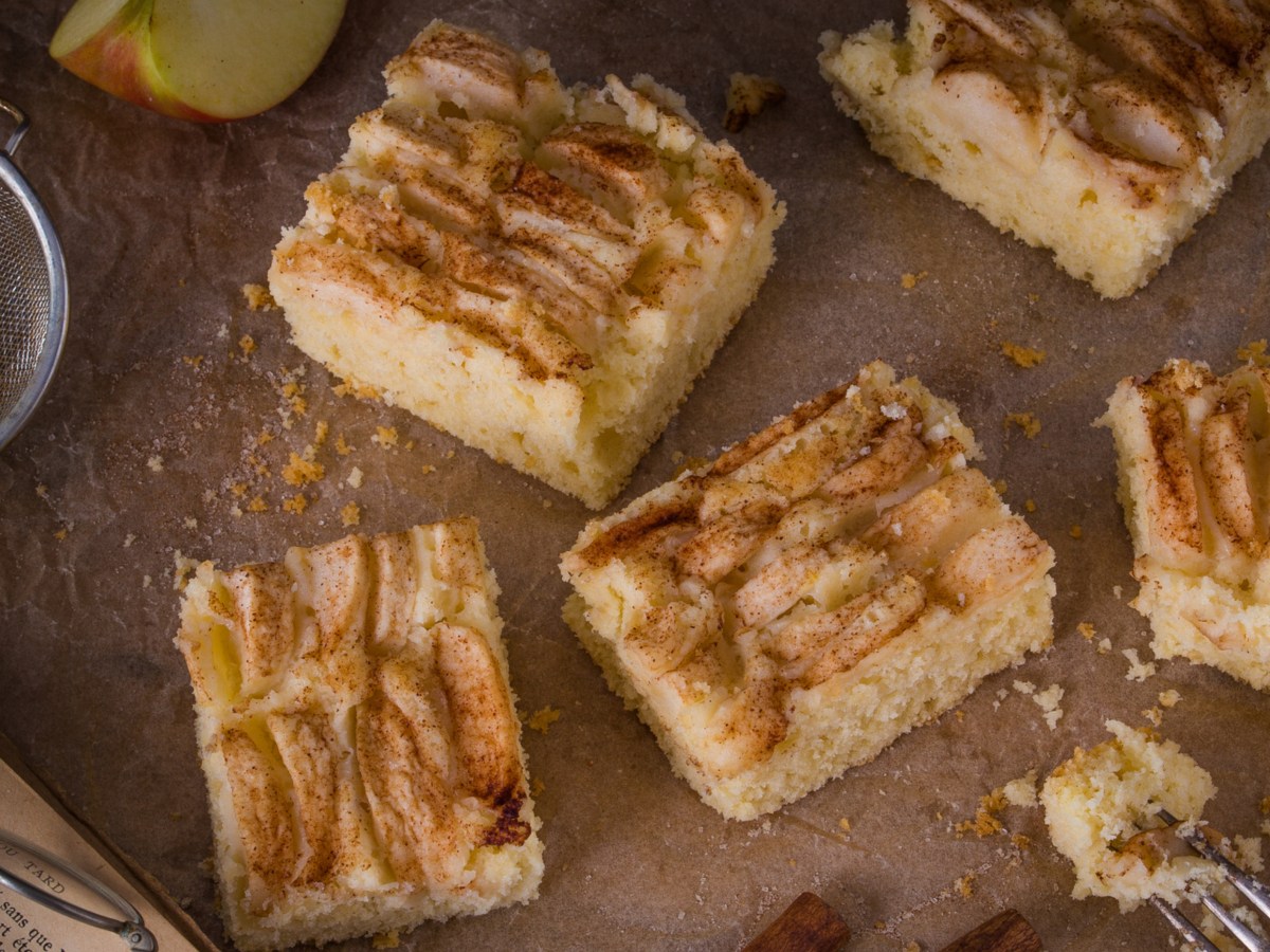 Apfelkuchen vom Blech auf braunem Tisch.