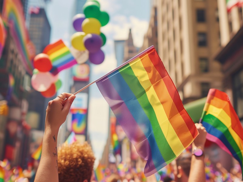 CSD Straßenfest mit Regenbogenflaggen durch eine Stadt.