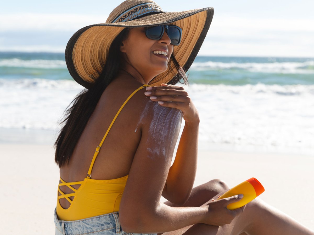 Frau beim Auftragen von Sonnencreme am Strand.