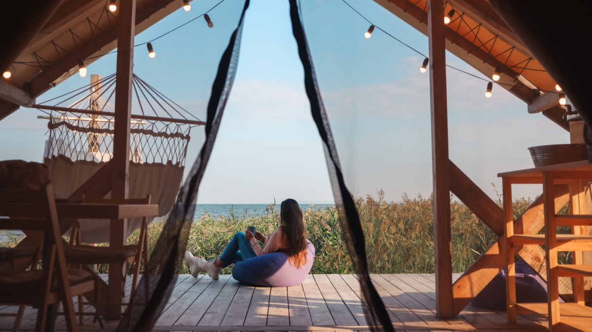 Frau sitzt auf Veranda von Glamping-Unterkunft