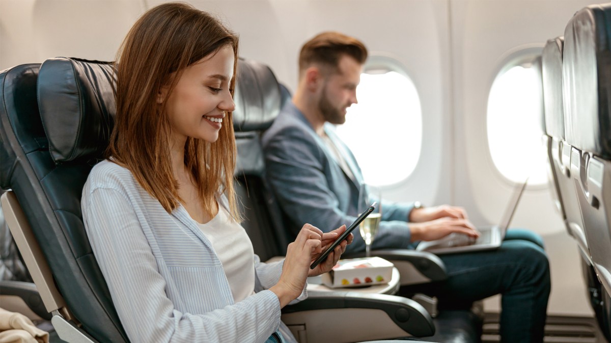 Frau, die mit ihrem Partner im Flugzeug sitzt und sich auf den Urlaub freut.