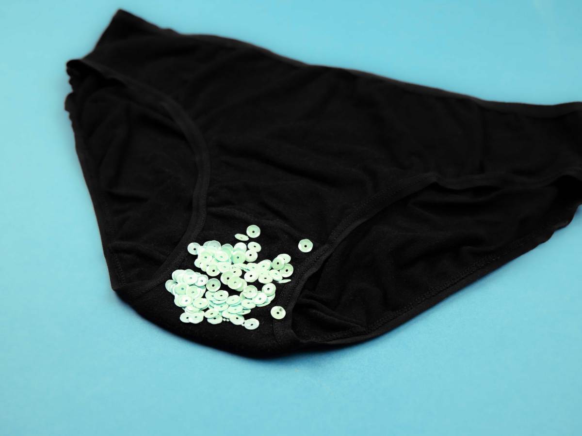 schwarzer slip auf blauem hintergrund mit pailetten als symbol für ausfluss