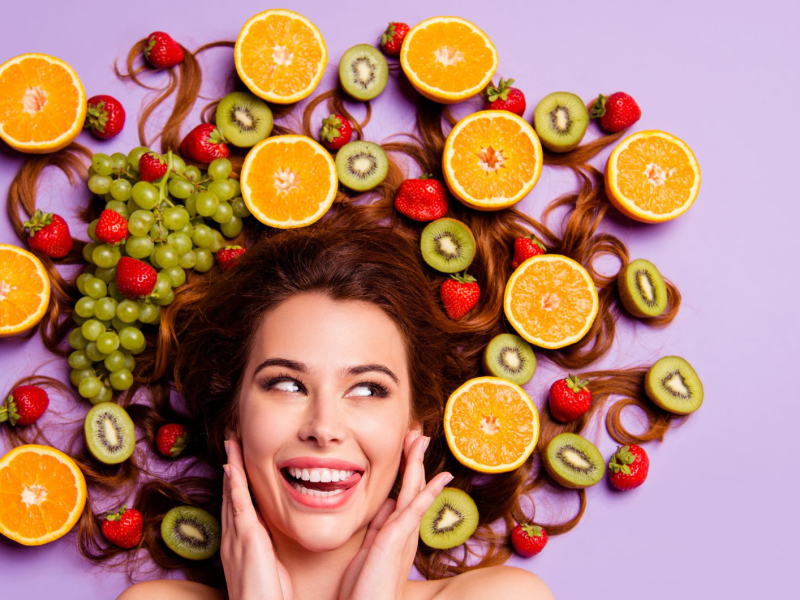 Frau, deren Haare von Früchten umgeben sind