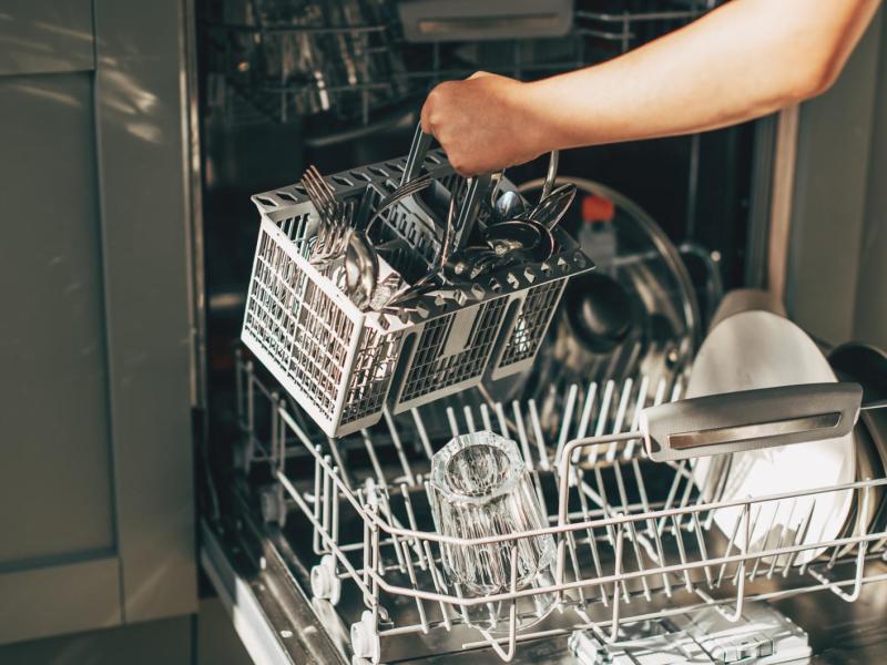 Frau räumt Spülmaschine aus.