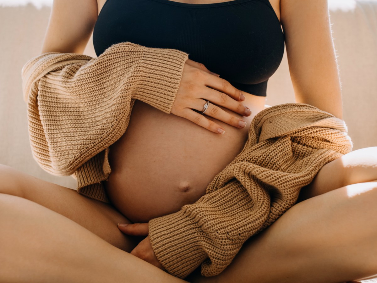 Schwangere Frau, die ihren Bauch liebevoll umarmt