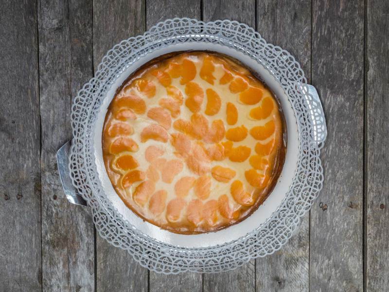 Schmandkuchen mit Mandarinen auf grauem Holzuntergrund