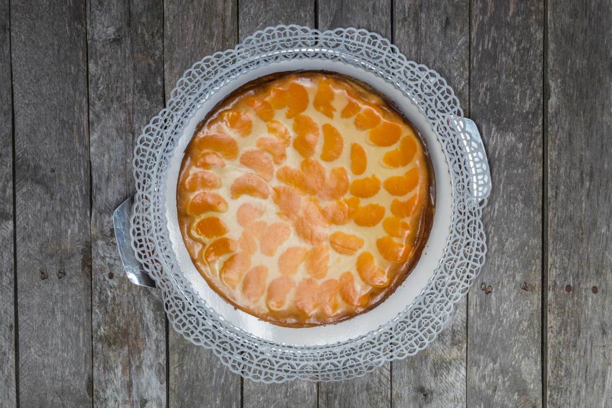 Schmandkuchen mit Mandarinen auf grauem Holzuntergrund