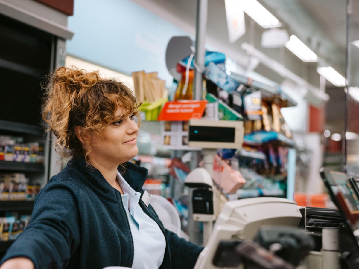 Frau an einer Supermarktkasse, die nett zur Seite l&auml;chelt