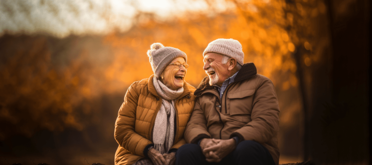 Oma und Opa auf einer Bank im Wald, die sich gegenseitig anlachen