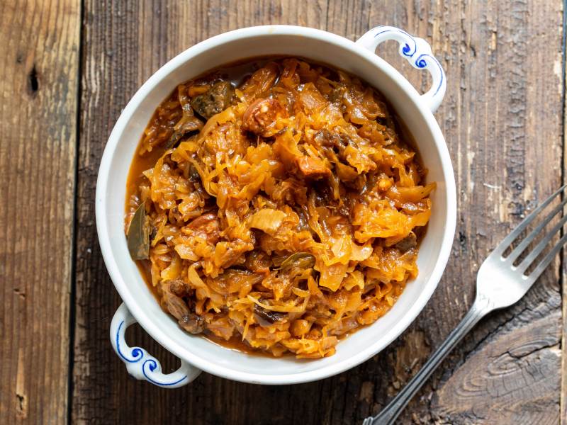 Aufnahme von oben: Schüssel mit einer Portion Bigos, daneben liegt eine Gabel.