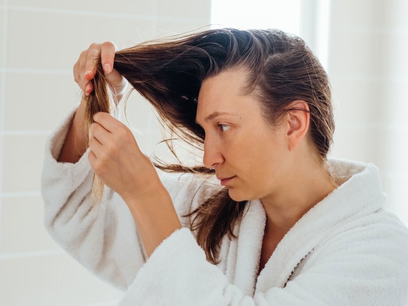 Frau die nach dem Haarewaschen ihre Spitzen begutachtet.
