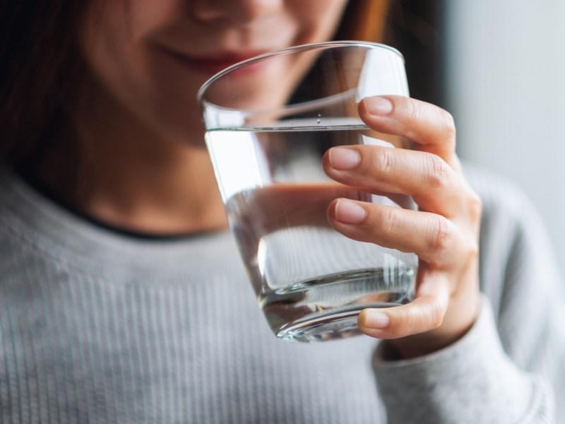 Frau trinkt aus Wasserglas.