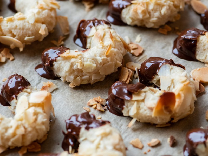 Mandelhörnchen mit Schokoenden auf einem Backblech.