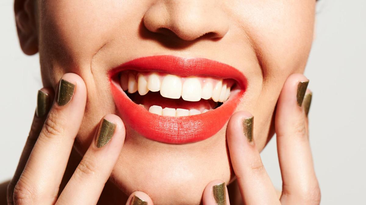 Frau mit Lippenstift lacht und hat ein strahlendes weißes Lächeln.