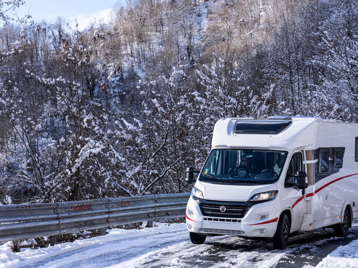 Wohnmobil auf verschneiter Stra&szlig;e in Winterlandschaft