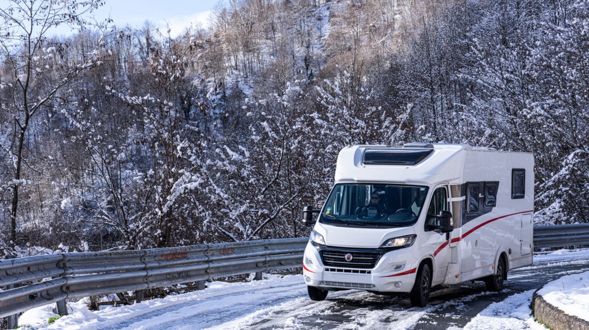 Wohnmobil auf verschneiter Straße in Winterlandschaft
